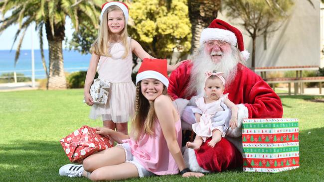 Bree, Eve and Emerson with Father Christmas pose for a photograph at Christies Beach, Adelaide in 2017. (AAP Photographer/ Keryn Stevens)