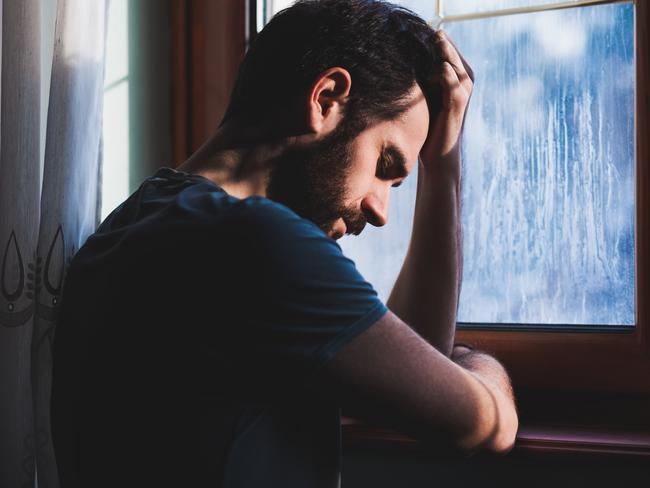 Young sad mad sitting by the window in regret istock RendezView