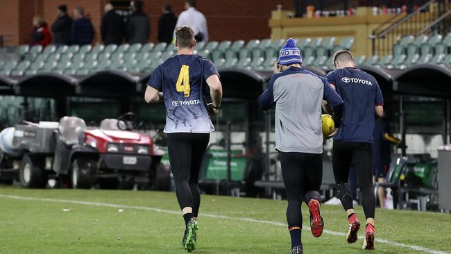 Josh Jenkins, Darcy Fogarty and Bryce Gibbs warm up before their running session on Adelaide Oval late on Saturday night. Picture: Sarah Reed.