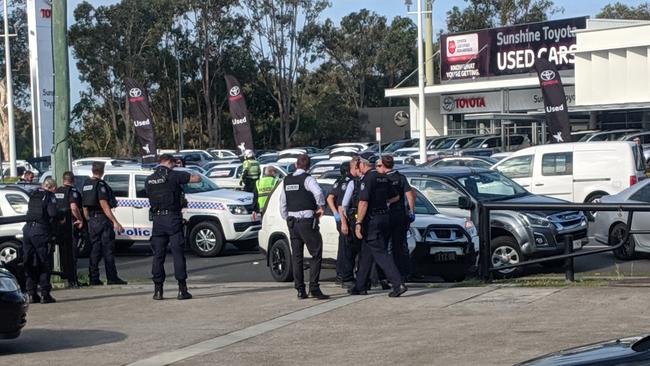 Dozens of armed police officers forcefully wrestling an allegedly offender to the ground after a wild police pursuit along Nicklin Way.