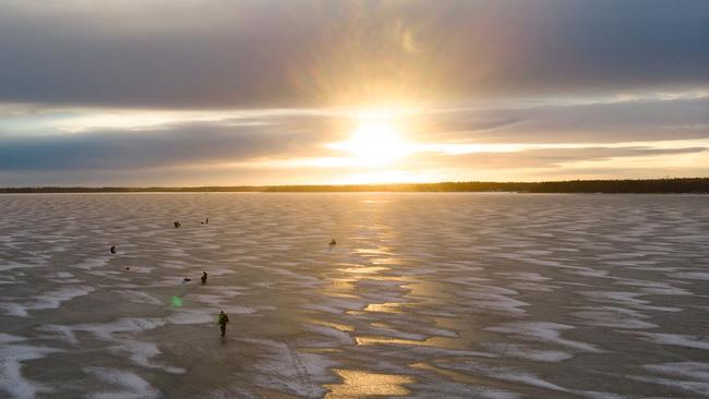 An aerial view shows men waiting near holes drilled into the frozen sea as they ice fish on the Gulf of Bothnia, near Vaasa, Western Finland where winter daylight lasts for about four hours. Picture: AFP