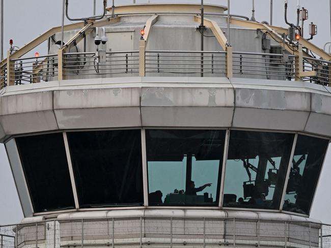 A man gestures inside the control tower of Reagan National Airport after an American Airlines flight crashed into the river after colliding with a US Army helicopter, near Washington, DC, on January 30, 2025. US President Donald Trump -- speaking as the bodies of 67 people were being pulled from Washington's Potomac River -- launched a political attack January 30, 2025 blaming diversity hires for the midair collision between an airliner and a military helicopter. (Photo by Oliver Contreras / AFP)