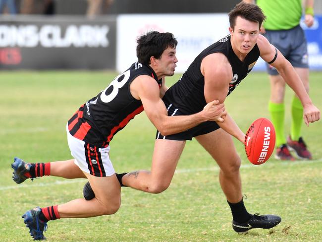 Port District’s Trent Heffernan gets the handball away while being tackled by Rostrevor Old Collegians’ Tim Baccanello on Saturday. Picture: AAP/ Keryn Stevens