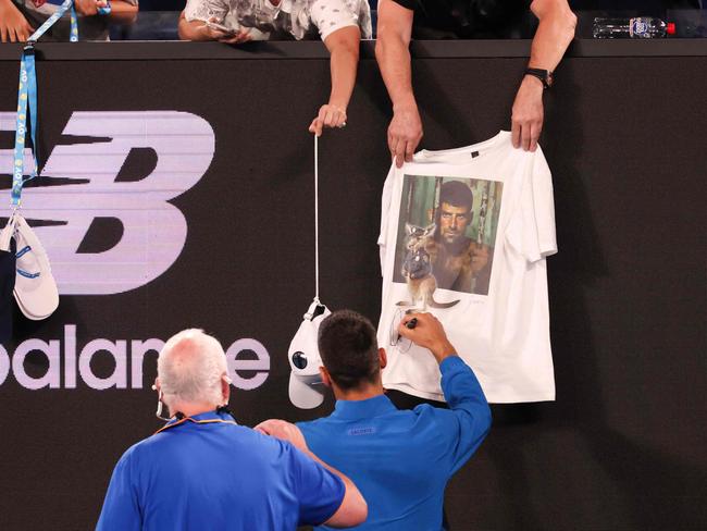 Serbia's Novak Djokovic signs a fan's t-shirt depicting his behind bars with a kangaroo cop after his men's singles match against Czech Republic's Jiri Lehecka. Picture: David Gray/AFP.