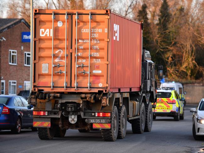 A police car escorts a British army truck, carrying a freight container laden with the car of Sergei Skripal, as it is driven from the Churchfields industrial estate in Salisbury. Picture: AFP