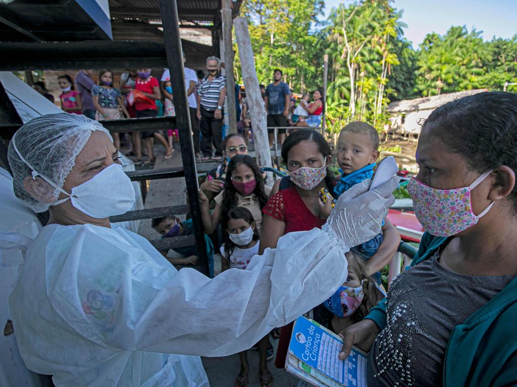 A health worker from the checks the body temperature of a patient at the riverside community of Selma Barra, Brazil. Picture: Tarso Sarraf/AFP.