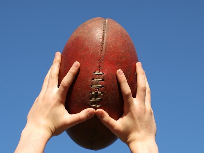 Young boy takes a mark catch above his head during an Australian Rules football AFL match. Generic image Picture: iStock