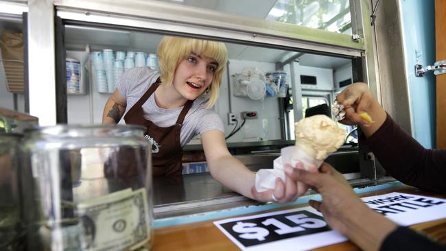 Caitlyn Faircloth, a worker with Molly Moon's Homemade Ice Cream, hands out free ice cream next to a tip jar, Monday, June 2, 2014, at a rally celebrating the passage of a $15 minimum wage measure outside Seattle City Hall in Seattle. The Seattle City Council passed a $15 minimum wage measure, Monday, but not until after debate over how long businesses will have to phase in the measure, and how tips, benefits, and other forms of compensation will be considered. (AP Photo/Ted S. Warren)