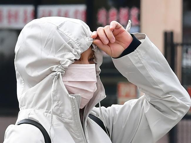 A woman wearing a face mask as a precaution against COVID-19, coronavirus, walks past stores in Monterey Park, California on March 10, 2020. - Los Angeles County announced the first case of COVID-19 through community transmission. (Photo by Frederic J. BROWN / AFP)