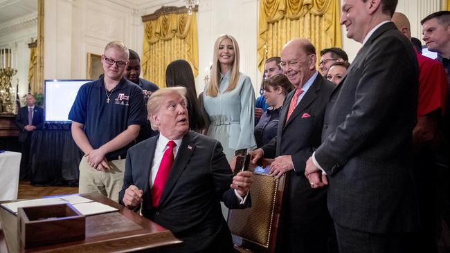 Donald Trump, accompanied by daughter Ivanka and Commerce Secretary Wilbur Ross, about to sign an executive order at the White House yesterday. Picture: AP