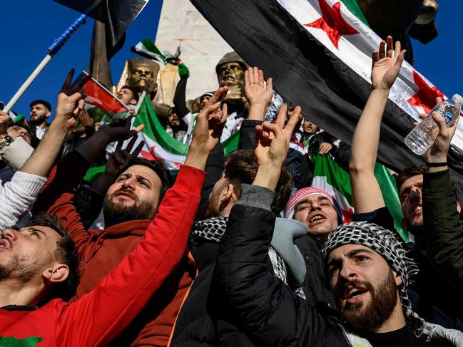 TOPSHOT - Syrian residents in Turkey wave Syrian opposition flags as they celebrate the fall of long-time ruler Bashar al-Assad after rebel fighters took control of the Syrian capital Damascus overnight, in Istanbul on December 8, 2024. Turkey's foreign minister said on December 8, 2024 the country wanted to help "guarantee security" in Syria after the fall of president Bashar al-Assad in the face of an offensive by Islamist-led rebels. (Photo by Yasin AKGUL / AFP)