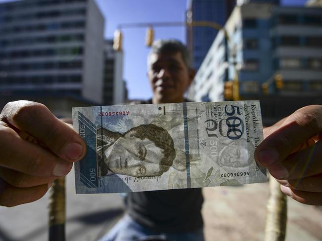 A street coffee vendor shows a new 500-Bolivar-note (74 cents of US dollar) in Caracas on January 16, 2017. The new 500-Bolivar-note is the first of a new family of currency that will progressively come into circulation. The South American country also has the highest inflation rate in the world, which IMF forecasts say could soon hit 475 percent. / AFP PHOTO / JUAN BARRETO