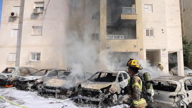 Israeli fire brigade teams douse the blaze in a parking lot outside a residential building following a rocket attack from the Gaza Strip.