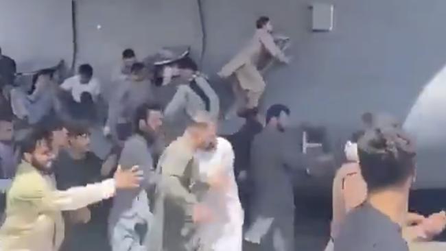 People run on the tarmac of Kabul international airport as a US military aircraft attempts to take off.