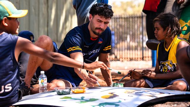 Adelaide’s Izak Rankine with kids in the APY Lands to inspire hundreds of children and youth to get excited about maths and science. Picture: AFC