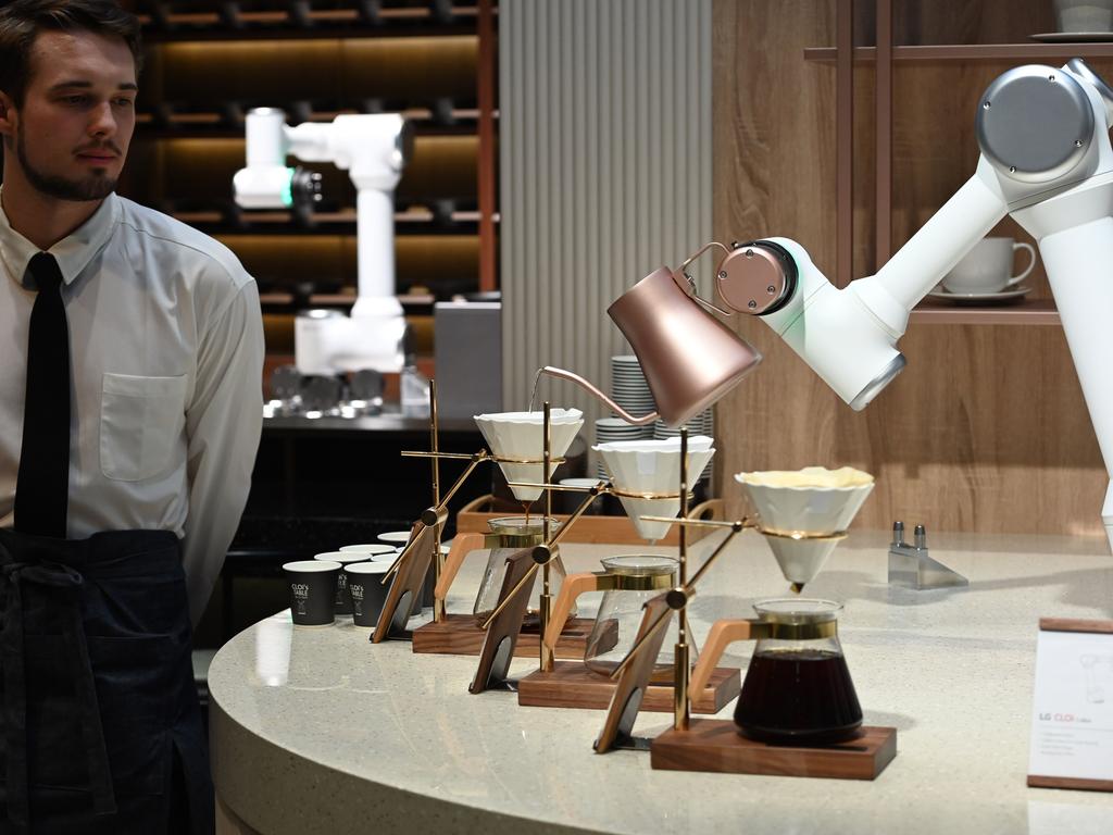 A man dressed in a barrista's outfit watches as an LG CLOi CoBot Barista robot makes pour-over coffee, at the LG booth, January 8, 2020 at the 2020 Consumer Electronics Show (CES) in Las Vegas, Nevada. - CES is one of the largest tech shows on the planet, showcasing more than 4,500 exhibiting companies representing the entire consumer technology ecosystem. (Photo by Robyn Beck / AFP)