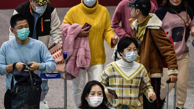 Passengers wearing respiratory masks walk across a terminal towards the check in counter on January 31, 2020 at Rome's Fiumicino Airport. Picture: Tiziana Fabi/AFP