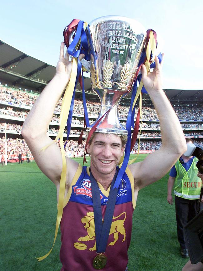 Brisbane Lions great Jason Akermanis, holding the 2001 AFL premiership cup trophy, has backed calls to fill the Gabba for the 2020 grand final.