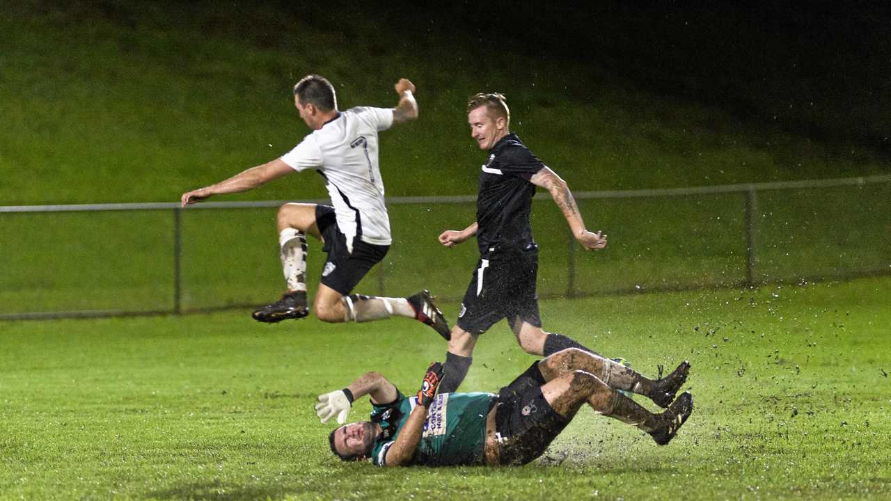 UNDER PRESSURE: Willowburn FC's Brodie Welch leaps over a sliding Alex Saunders (Willowburn White) during their Toowoomba Football League Premier Men's match at Commonwealth Oval on Saturday night. Picture: Kevin Farmer