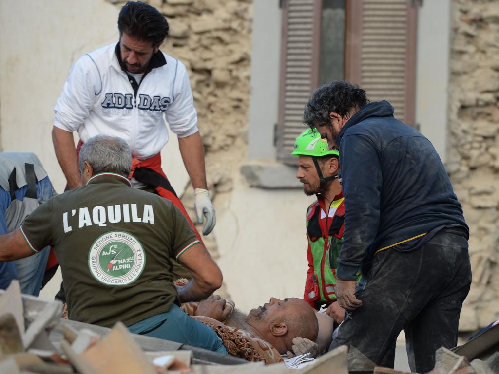 Rescuers help a victim in a damaged building after a strong earthquake hit Amatrice on August 24, 2016. Picture: AFP