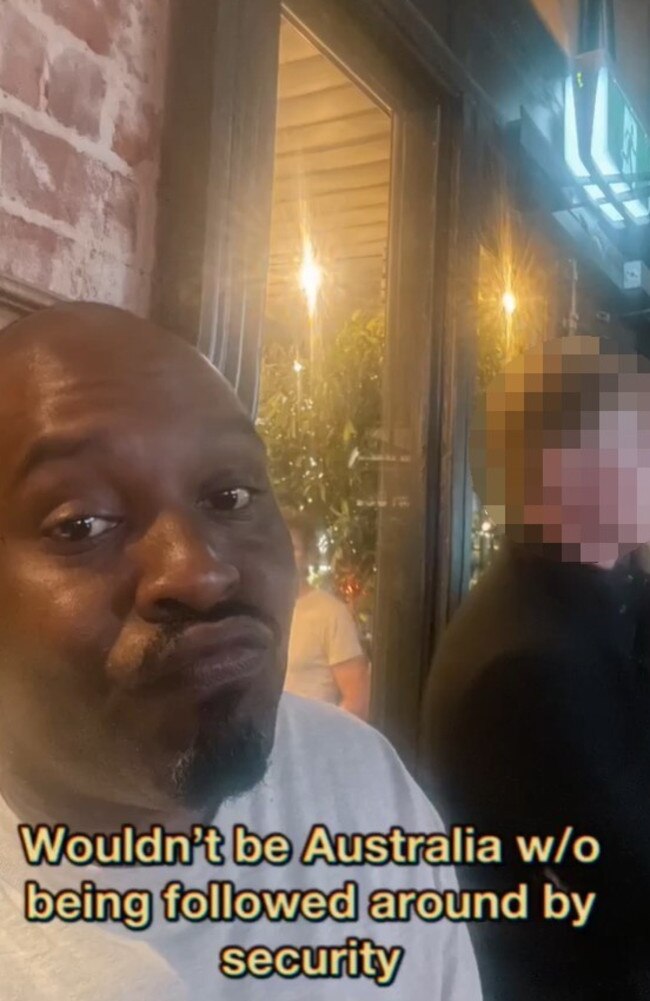 British comic Dane Baptiste claimed the man behind him (who news.com.au has blurred) was a security guard that was following him around.