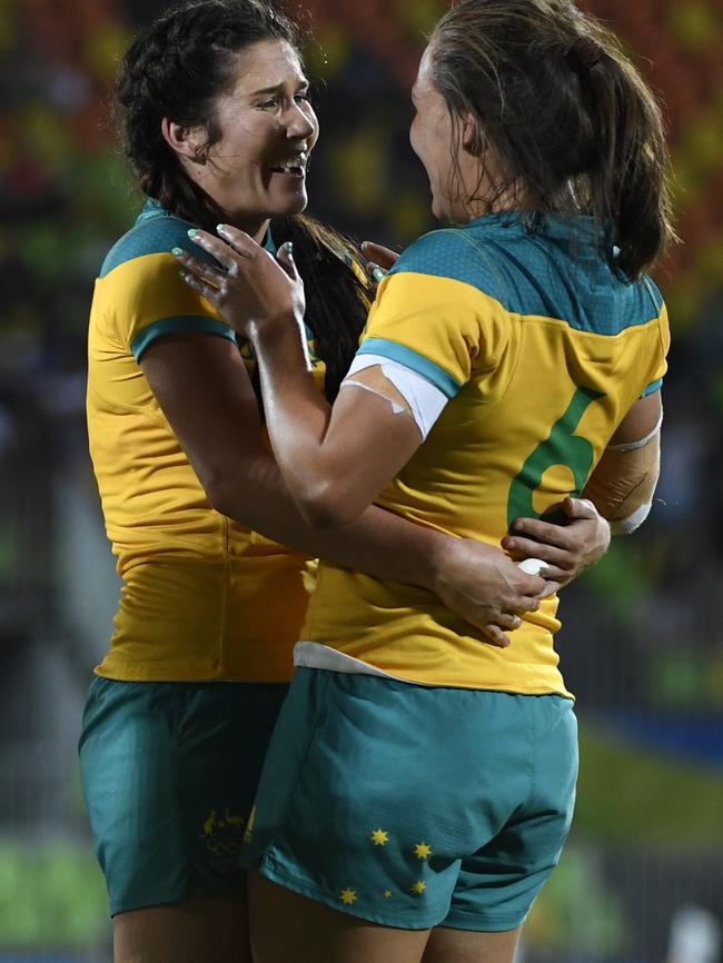 Australia's Charlotte Caslick (L) and Australia's Evania Pelite celebrate victory in the women’s rugby sevens gold medal match between New Zealand and Australia during the Rio 2016 Olympic Games at Deodoro Stadium in Rio de Janeiro on August 8, 2016. / AFP PHOTO / John MACDOUGALL