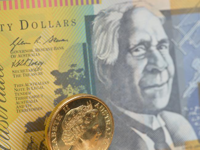 Byron Bay, NSW, Australia January 25 2015: Focus on a one dollar coin with a fifty dollar note behind, cash, money, generic