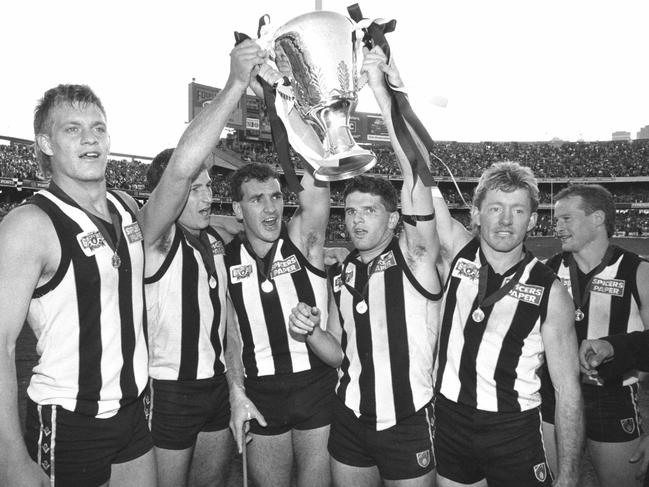 Damian Monkhorst, Craig Kelly, Darren Millane, Scott Russell, Shane Kerrison, Doug Barwick, Gavin Brown (obscured) and Craig Starcevich with the premiership cup. 1990 Grand Final. Collingwood v Essendon. MCG.