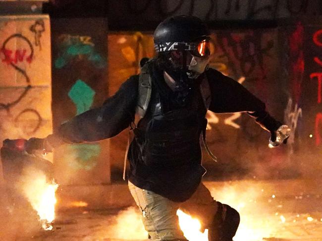 PORTLAND, OREGON - JULY 22: A protester throws flaming trash toward the Mark O. Hatfield U.S. Courthouse after breaking through a newly-reinforced perimeter fence on July 22, 2020 in Portland, Oregon. The night marked 56 days of protests in Portland following the death of George Floyd in police custody.   Nathan Howard/Getty Images/AFP == FOR NEWSPAPERS, INTERNET, TELCOS & TELEVISION USE ONLY ==