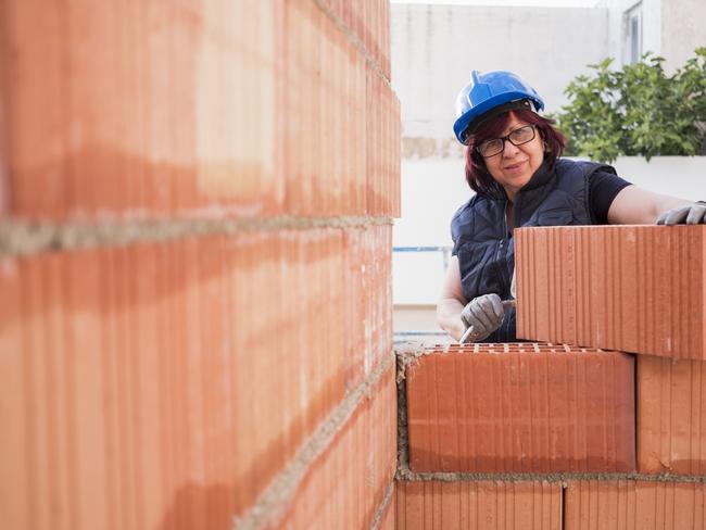 mature woman bricklayer lays bricks in the construction and remodeling of the terrace room of a house. Picture: iStock