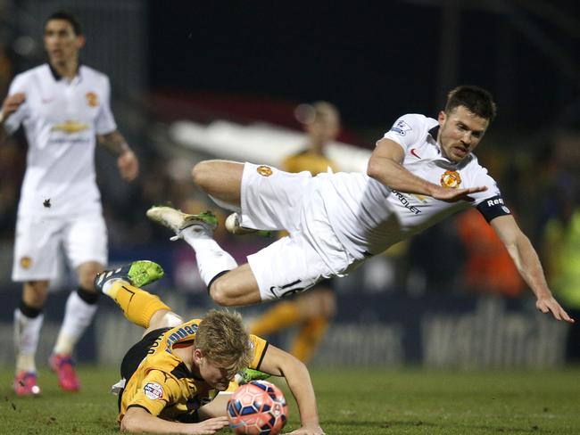 Manchester United's English midfielder Michael Carrick (R) falls over Cambridge Unite's English midfielder Cameron McGeehan.