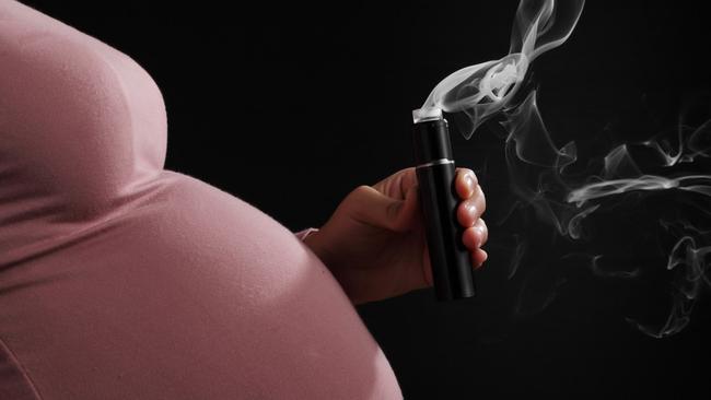 Close up pregnant woman smoking e-cigarette isolated on black background