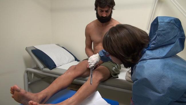 John Peros gives hair samples to police in Brisbane after his arrest.