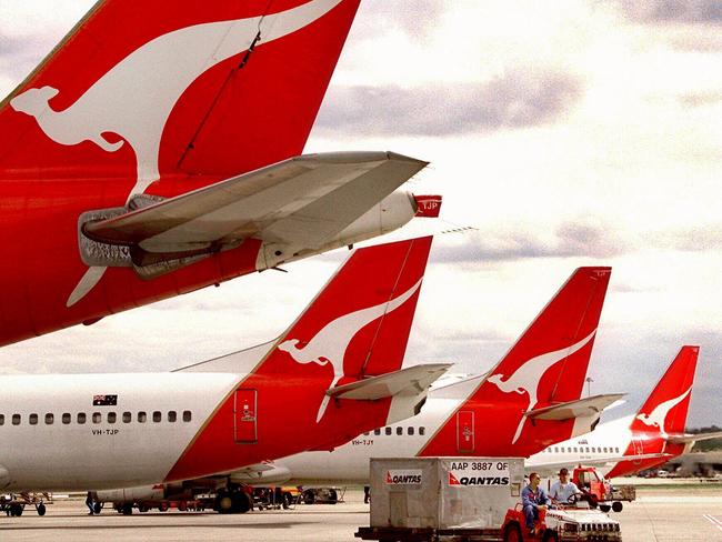 Qantas aircraft tails at Kingsford Smith Airport in Sydney as baggage handlers deliver luggage. plane airline logo tail/Qantas/Airways/Ltd