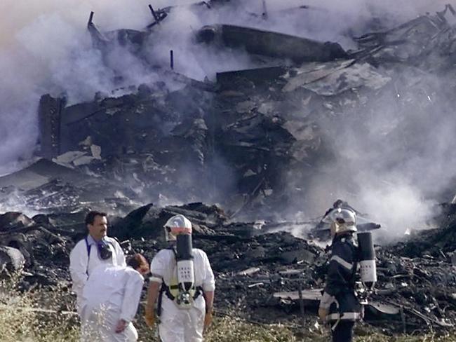 Rescue workers stand near the debris of the hotel on which an Air France Concorde en route to New York crashed in Gonesse, outside Paris shortly after take off. Picture: Laurent Rebours.