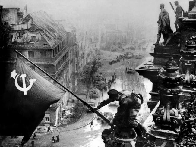 A Soviet soldier raising the Red Flag over Berlin's Reichstag, after the allied forces entered the city ending World War II. Russian experts scoured the Brandenberg research facility for evidence of Hitler’s atomic bomb program. Picture: AFP