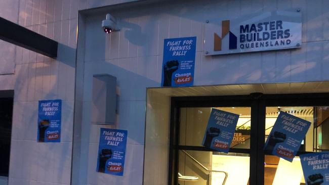 CCTV cameras capturing unionists plastering the front of the Master Builders office with "change the rules" rally posters