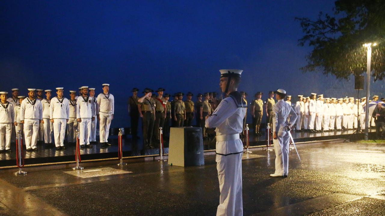 Service members of HMAS Cairns and the 51st Battalion stand at attention in the wet weather. Picture: Brendan Radke