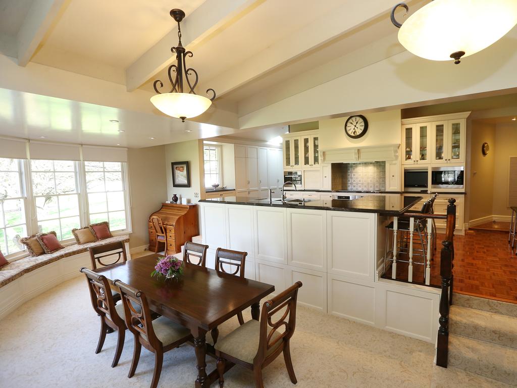 An open-plan kitchen, dining and living zone features a fireplace and window that frames views of the garden and floods the room with natural light. Picture: Andy Rogers