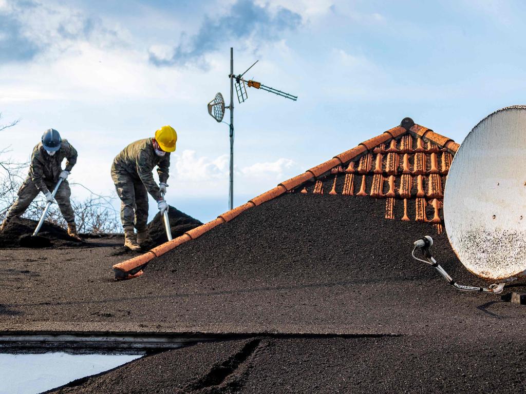 Workers clean ash-covered roofs in Las Manchas. Picture: Luismi Ortiz/UME/AFP