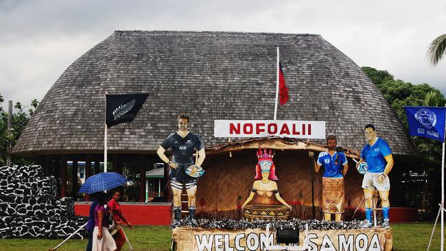 Locals walk past handmade posters made for the arrival of the All Blacks in Apia, Samoa.