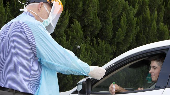 Doctor Rod Pearce from Medical HQ GP Family Practice administers a COVID-19 test to Lauchlan Milne. Dr Pearce and his staff today are administering Flu vaccinations and COVID-19 tests in the carpark. Patients can roll down the window and get tested or sit in the carpark and be immunised against influenza with the 2020 vaccine. Picture: Emma Brasier/AAP