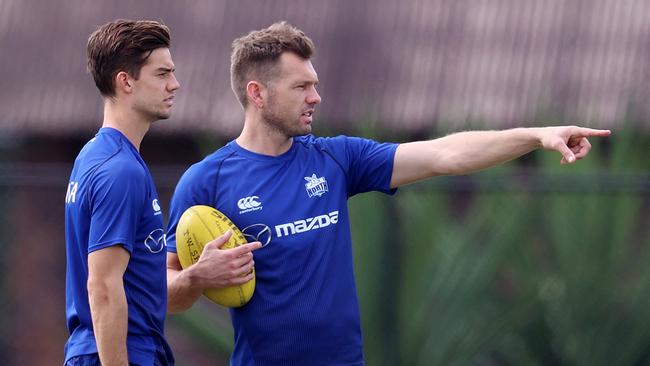 Jy Simpkin chats to teammate Shaun Higgins at North Melbourne training.