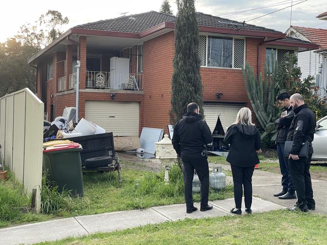 Detectives outside the scene of house fire at Orchard Rd, Fairfield. Two gas cylinders can be seen in the foreground. Picture: Paul Brescia