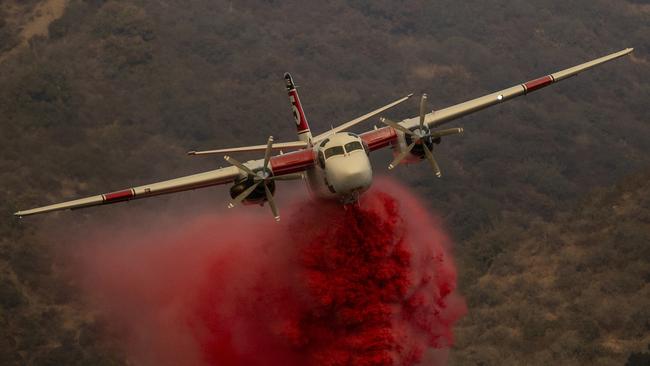 A Cal Fire S-2T firefighting tanker releases retardant while battling the Palisades fire in the Mandeville Canyon neighbourhood of Los Angeles. (Picture: Stephen Lam/San Francisco Chronicle via AP