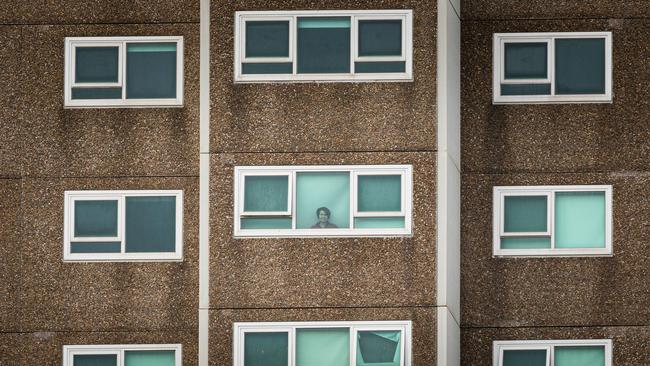 A lone woman looks out the window of her apartment at the North Melbourne Public housing flats. Picture: Getty