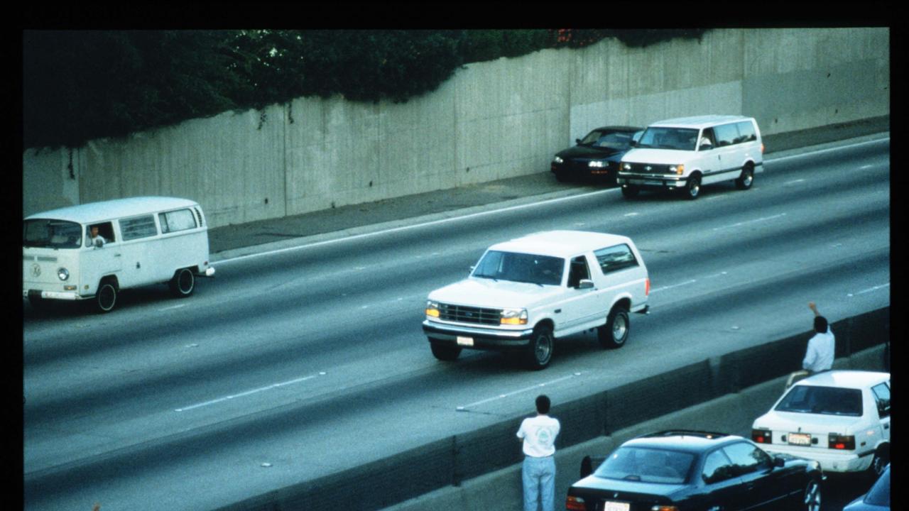 Motorists wave as police cars pursue the Ford Bronco driven by Al Cowlings, carrying fugitive murder suspect OJ Simpson, on a 90-minute slow-speed car chase. Picture: Jean-Marc Giboux/Liaison