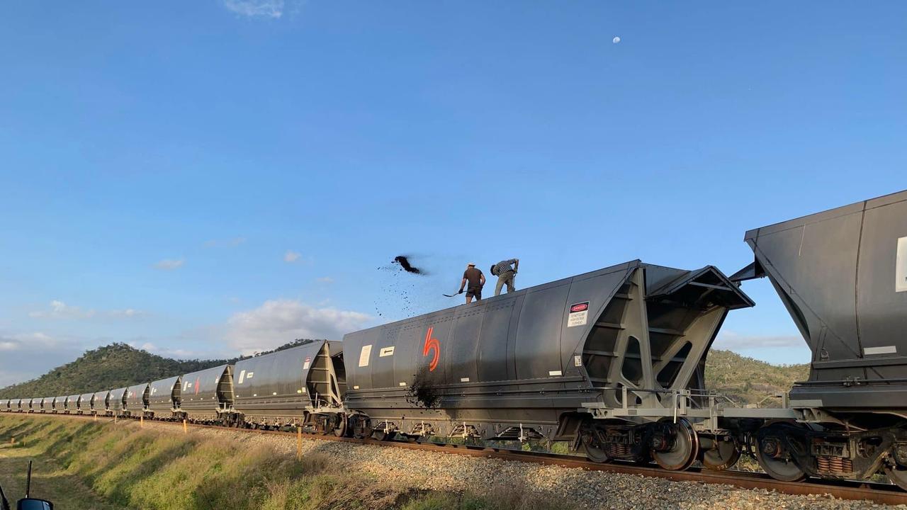 Activists Kyle Magee and Franz Dowling shovel coal from a Bowen Rail Company wagon onto the ground in December 2021. Picture: Contributed