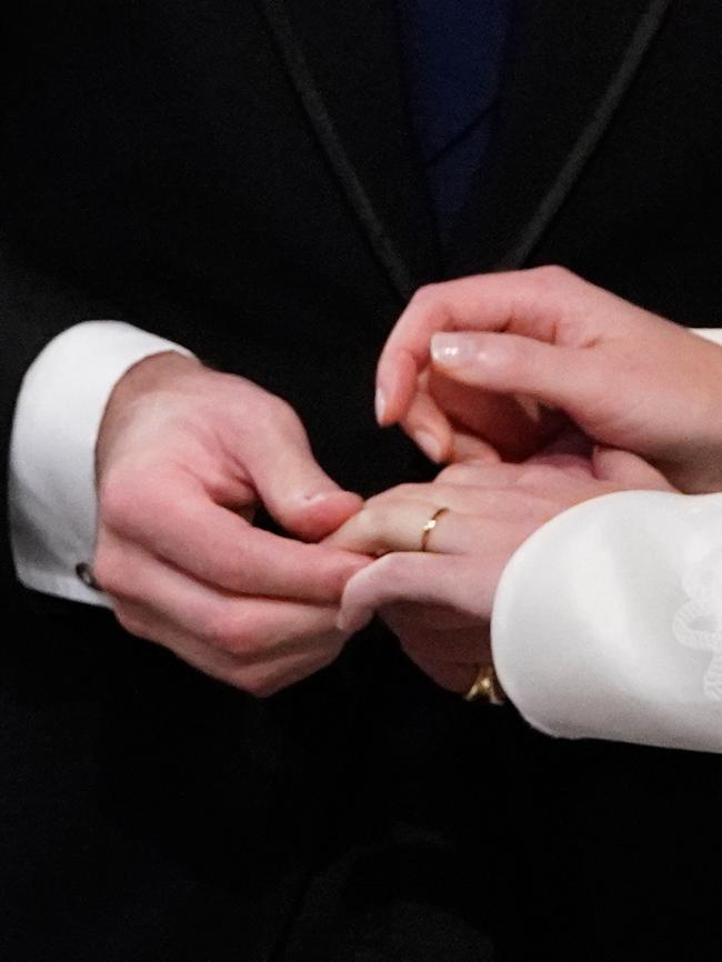 The groom places a wedding band on the finger of his bride. Picture: AFP