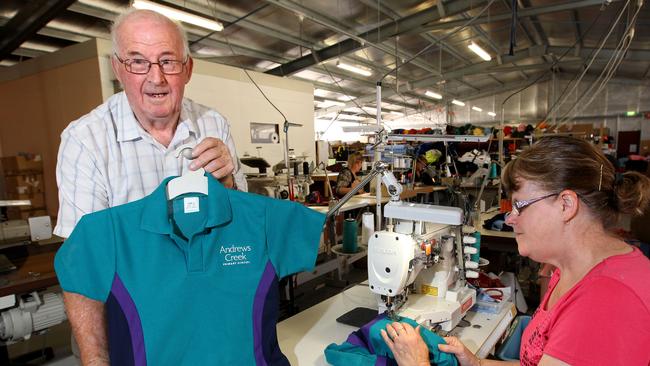 Tasmanian Clothing Company managing director Graeme Davis holds up a finished school shirt as machinist Irene Maney completes another at the Spreyton factory.